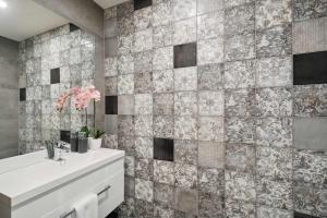 een badkamer met een wastafel en een betegelde muur bij Remarkable Lake View in Queenstown