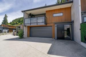 een huis met een grote garage en een balkon bij Remarkable Lake View in Queenstown