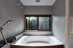 a bath tub in a bathroom with a window at TID TID Yamanakako in Yamanakako