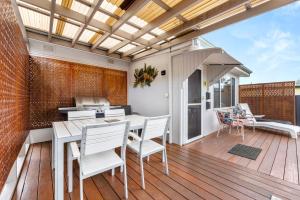 un patio con mesa y sillas en una terraza de madera en Osprey - Pet Friendly Waterfront, en Callala Bay