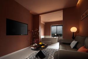 a living room with a couch and a television on a wall at Yinshi Yunshe Private Hot Spring Villa in Dujiangyan in Dujiangyan