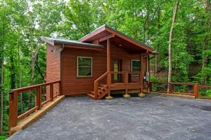 eine kleine Hütte im Wald mit einer Veranda in der Unterkunft New Cozy Mountain Chalet Hot Tub Near Downtown in Gatlinburg + 59 Fotos