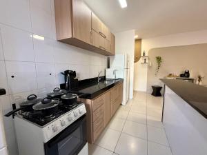 Una cocina con estufa y refrigerador blanco. en Apartamento em região central com 3 smart TVs - UFV a 1 km, en Viçosa