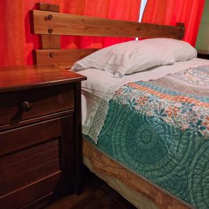 a bed with a wooden headboard next to a wooden table at Como florcita en la mata in Villarrica