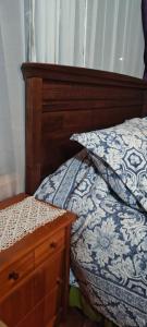 a bedroom with a bed with a wooden headboard and a night stand at Como florcita en la mata in Villarrica
