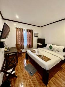 a bedroom with a bed and a desk and a television at Sophias Beach Guest House in El Nido