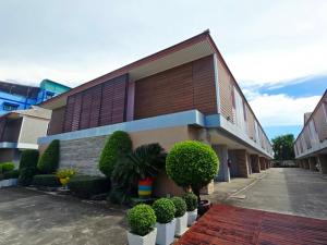 a building with bushes and trees in front of it at Save Hotel เซฟ โฮเทล in Chon Buri