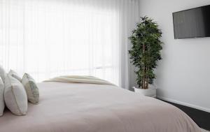 - une chambre dotée d'un lit blanc avec des oreillers et une plante dans l'établissement Surfrider Hideaway - steps to beach, à Mudjimba 24 autres photos