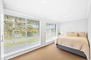 a bedroom with a bed and large windows at Holiday on Noble in Dalmeny