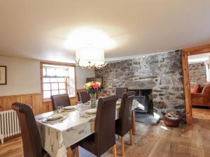a dining room with a table and chairs and a stone wall at 83 Seatown in Buckie