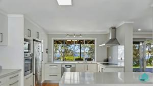Una cocina con gabinetes blancos y una ventana grande. en WishStay Waterfront Luxury Retreat - private pool, en Morisset East