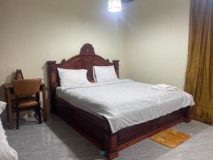 a bed with a wooden headboard in a room at Joeshomestaysiemreap in Phumĭ Bœ̆ng (1)