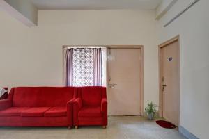 a red couch in a room with a window at Hotel O Tumpa Inn in Kolkata