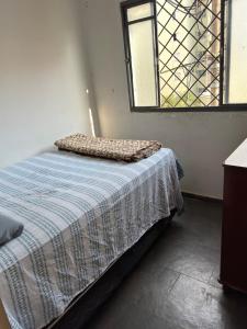 a bedroom with a bed with a blanket and a window at Apartamento Residencial Alice in Uberaba +7 photos