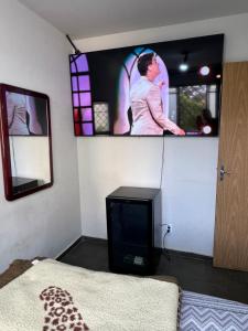 Zimmer mit einem TV an der Wand und einem Bett in der Unterkunft Residencial Alice in Uberaba