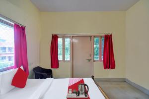 a bedroom with a bed with red drapes at Hotel O Tumpa Inn in Kolkata
