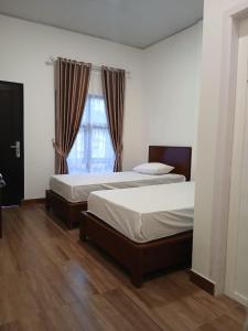 a bedroom with two beds and a window at Pandava House Lombok in Lombok International Airport
