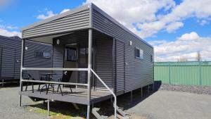a black tiny house with a porch and a deck at Guyra Club Cabins in Guyra
