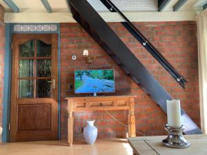 une télévision posée sur une table dans une pièce avec un mur de briques dans l'établissement 6 pers - Modern holiday home with garden, close the Lauwersmeer, à Oostmahorn