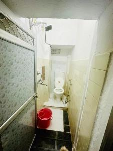 ジャイサルメールにあるMirvana Guest House & Camel safariの小さなバスルーム(トイレ、赤いバケツ付)