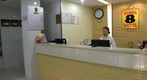 a woman sitting at a counter with a laptop at Super 8 Hotel Jinan Railway Station Square in Jinan
