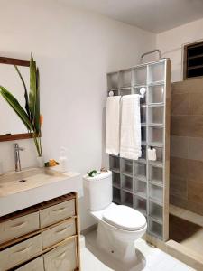a white bathroom with a toilet and a sink at Logement de charme, au soleil et proche de la mer in Moorea