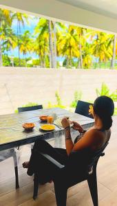 a woman sitting at a table with her feet up at Logement de charme, au soleil et proche de la mer in Moorea