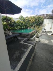 a swimming pool with a table and an umbrella at Kubusawah Guest House in Seminyak