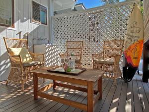 Una terraza de madera con una mesa y sillas y una tabla de surf. en A Amity Beach Baby, en Amity Point