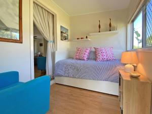 Un dormitorio con una cama con almohadas rosas. en A Amity Beach Baby, en Amity Point