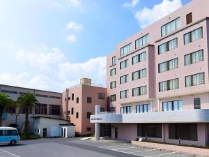 a large pink building with a car parked in a parking lot at Hotel New Otsuka in Shirako