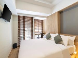 a bedroom with a large white bed and a television at GOLDEN TULIP ESSENTIAL PIK2 JAKARTA in Tangerang