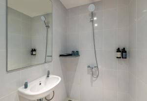 a white bathroom with a sink and a shower at GOLDEN TULIP ESSENTIAL PIK2 JAKARTA in Tangerang