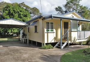 una casa amarilla con porche y garaje en Berrimilla, en Amity Point