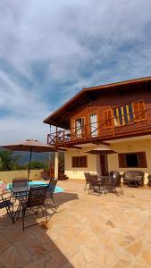 a house with chairs and a table in front of it at Mar a Vista Suítes ILHABELA in Ilhabela