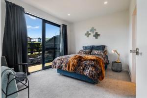 a bedroom with a bed and a large window at Puhinui House in Warkworth