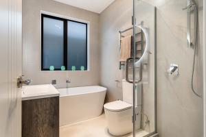 a bathroom with a tub and a toilet and a sink at Puhinui House in Warkworth +10 photos