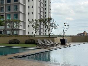 Una piscina con tumbonas al lado de un edificio. en Paradigm Residence by YML Home, en Johor Bahru