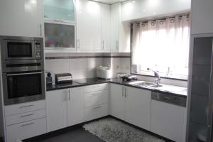 une cuisine avec des armoires blanches, un évier et une fenêtre dans l'établissement Apartamento Superior Helena's Porto Corner, à Vila Nova de Gaia