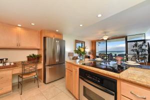 Una cocina con refrigerador de acero inoxidable y una mesa. en Kahana Reef 117 · KR 117 Renovated OceanFront 1BD w Ocean Views, en Kahana