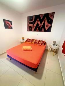 a bedroom with a large orange bed in a room at Une pause au soleil et proche de la mer in Moorea
