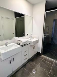 Un baño con dos lavabos y un espejo grande. en Coastal Calm, en Kawana Waters