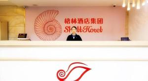 a man standing in front of a wall with a sign at Shell Hotel Shanghai Expo Changqing Road Metro Station in Shanghai