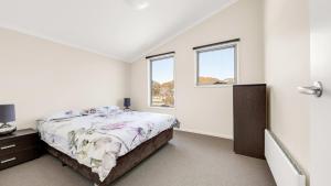 a white bedroom with a bed and two windows at Cool Runnings in Dinner Plain