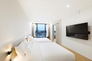 a hotel room with two beds and a flat screen tv at Pohang Hound Hotel Songdo Beach in Samgong