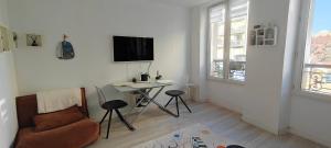 Una sala de estar con un sofá, una mesa y un televisor. en Appartement paisible, en Clichy