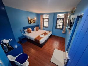 Un dormitorio azul con una cama y una silla. en Wow-Guesthouse soi 19, en Bangkok