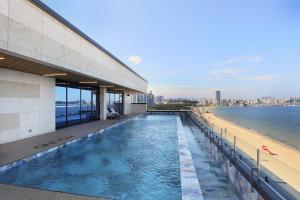 a swimming pool on the side of a building next to a beach at Pohang Hound Hotel Songdo Beach in Samgong