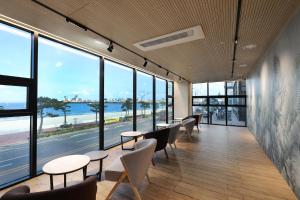 a row of tables and chairs in a room with large windows at Pohang Hound Hotel Songdo Beach in Samgong