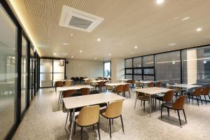 a cafeteria with tables and chairs and windows at Pohang Hound Hotel Songdo Beach in Samgong